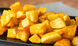 Patate al forno veloci, dorate e croccanti, servite su un piatto nero. Perfette per un contorno rapido e gustoso.
