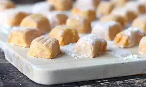 Gnocchi di zucca fatti in casa, morbidi e colorati, pronti per essere cucinati su un tagliere di legno.