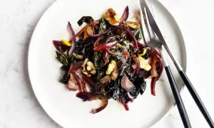 Bietole in padella con cipolle rosse caramellate e noci croccanti, un piatto colorato e saporito.