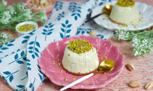 Delizioso semifreddo al pistacchio, guarnito con crema e granella di pistacchi, servito su un piatto rosa.