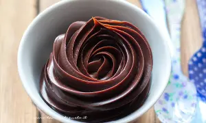 Una spirale perfetta di ganache al cioccolato, lucida e invitante, in una ciotola bianca.
