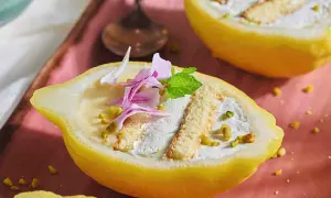 Delizia al limone: un dolce fresco e invitante, servito in un limone scavato, con crema, pan di spagna e pistacchi.