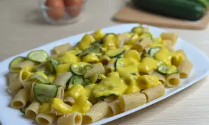 Piatto di rigatoni conditi con una cremosa salsa gialla e zucchine a rondelle. Una deliziosa carbonara di zucchine pronta da gustare.