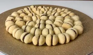 Un vassoio dorato pieno di deliziosi baci di dama, biscotti friabili con un cuore di cioccolato.