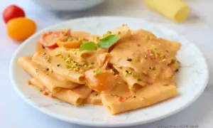 Paccheri cremosi con pomodorini e pistacchi, un piatto di pasta con stracciatella che invita a un morso goloso.