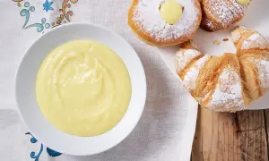 Una ciotola di crema pasticcera senza uova, perfetta per farcire croissant e bomboloni spolverati di zucchero a velo.
