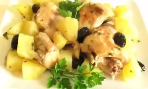 Coniglio in padella con patate e olive nere, guarnito con prezzemolo fresco. Un piatto saporito e invitante.