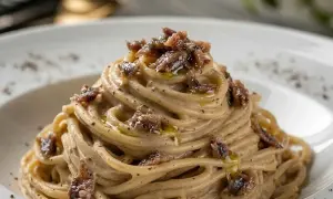 Spaghetti burro e alici, un piatto cremoso e saporito, con fili di pasta avvolti in una salsa delicata e guarniti con pezzetti di acciughe.