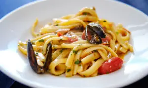 Un piatto invitante di scialatielli ai frutti di mare, con cozze, pomodorini e prezzemolo fresco.