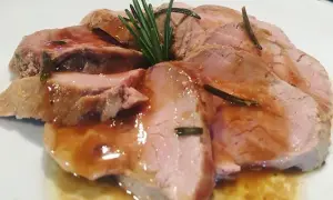 Fette succulente di filetto di maiale al forno, bagnate in un sughetto saporito e guarnite con rosmarino fresco.