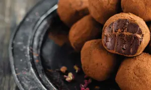 Un mucchio di tartufini al cioccolato ricoperti di cacao, uno aperto rivela il ripieno fondente.
