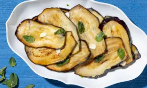 Fette di melanzane grigliate, condite con aglio e menta fresca, un contorno di verdure saporito e colorato.