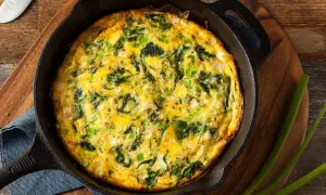 Frittata al forno con spinaci e cipollotti, appena sfornata in padella di ghisa, pronta per essere gustata.