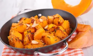Zucca in agrodolce cotta in padella, guarnita con semi di zucca e erbe aromatiche. Un contorno autunnale saporito.