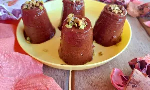 Deliziosi budini cachi e cacao, guarniti con pistacchi tritati, su un piatto giallo.