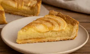 Una fetta di crostata di mele, con la sua base dorata, ripieno cremoso e mele affettate in superficie, pronta per essere gustata.
