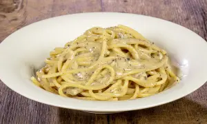 Un piatto di spaghetti cremosi al cacio e pepe, conditi con pepe nero macinato fresco.