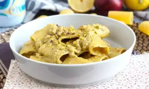 Un piatto di pasta in bianco condita con una crema di pistacchio e guarnita con granella dello stesso frutto secco.