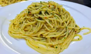 Spaghetti conditi con aglio, olio e peperoncino, guarniti con prezzemolo fresco. Un classico piatto italiano pronto da gustare.