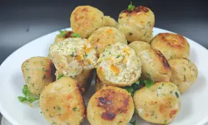 Un piatto di polpette di pollo dorate, con pezzetti di carota e prezzemolo visibili all'interno. Alcune sono leggermente aperte, mostrando la morbidezza.