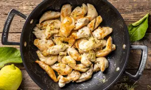 Pezzetti di petto di pollo dorati in padella, conditi con limone e erbe aromatiche. Un'idea veloce per le tue ricette di petto di pollo.