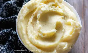 Una ciotola di cremoso pure di patate, guarnito con pepe nero macinato, su un tessuto scuro.