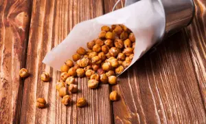 Ceci croccanti, preparati nella friggitrice ad aria, versati da un cono di carta su un tavolo di legno.