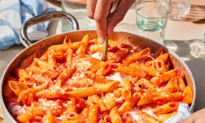 Un primo piatto invitante: pasta alla sorrentina fumante, con pomodoro e mozzarella filante, pronta per essere servita.