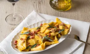 Piatto di casoncelli alla bergamasca conditi con burro, salvia e pancetta croccante.