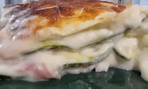Porzione di lasagne di zucchine cremose e dorate, con strati di verdura e besciamella filante.
