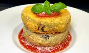 Due cordon bleu di melanzane impilati, dorati e croccanti, su un letto di salsa di pomodoro e basilico fresco.