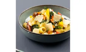 Piatto di pasta con verdure fresche, pomodorini, peperoni gialli e scaglie di parmigiano.