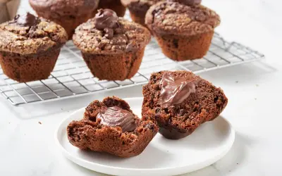 Muffin al cioccolato soffici e golosi, uno aperto rivela un cuore cremoso. Perfetti per una pausa dolce.