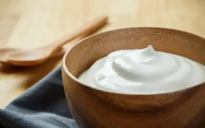 Una ciotola di legno piena di soffice crema al latte, pronta per essere gustata. Due cucchiai di legno sullo sfondo.