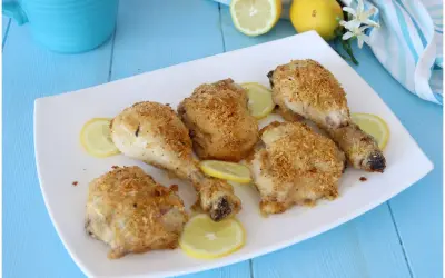 Cosce di pollo al limone croccanti e dorate, servite su un piatto bianco con fette di limone fresco.
