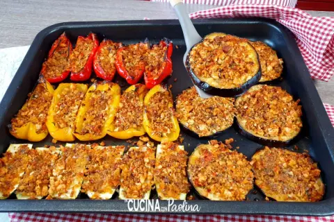 Delizioso piatto di verdure gratinate al forno: peperoni rossi e gialli ripieni, zucchine a rondelle e melanzane a fette, tutti dorati e croccanti.