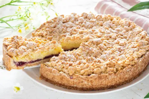 Deliziosa sbriciolata alla crema con un ripieno di marmellata di frutti di bosco, cosparsa di zucchero a velo.