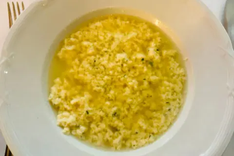 Stracciatella alla romana in una ciotola bianca, un piatto caldo e confortante con uova, parmigiano e prezzemolo.