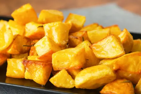 Patate al forno veloci, dorate e croccanti, servite su un piatto nero. Perfette per un contorno rapido e gustoso.