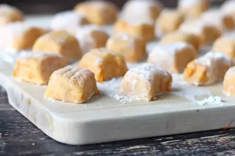 Gnocchi di zucca fatti in casa, morbidi e colorati, pronti per essere cucinati su un tagliere di legno.