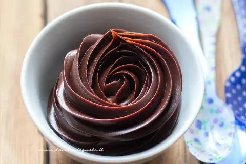 Una spirale perfetta di ganache al cioccolato, lucida e invitante, in una ciotola bianca.