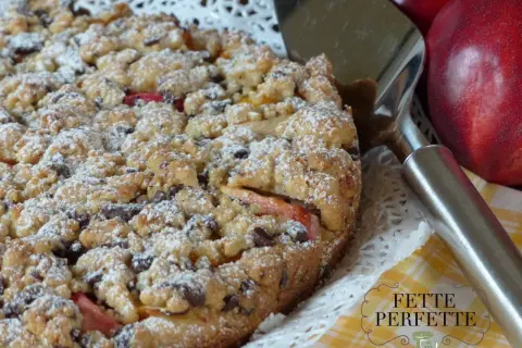 Torta sbriciolata con pesche e gocce di cioccolato, perfetta per chi ama le ricette con le pesche. Un dolce rustico e goloso.
