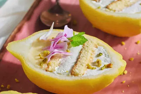 Delizia al limone: un dolce fresco e invitante, servito in un limone scavato, con crema, pan di spagna e pistacchi.