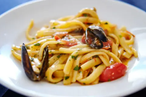 Un piatto invitante di scialatielli ai frutti di mare, con cozze, pomodorini e prezzemolo fresco.