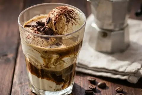 Un delizioso affogato al caffè, con gelato alla vaniglia, cacao e scaglie di cioccolato, pronto per essere gustato.
