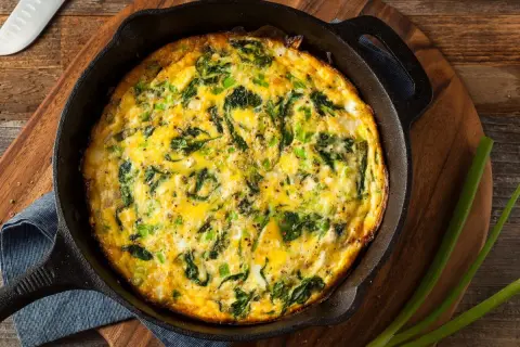 Frittata al forno con spinaci e cipollotti, appena sfornata in padella di ghisa, pronta per essere gustata.