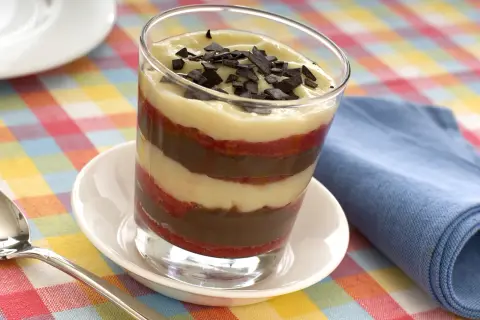 Delizioso bicchiere di zuppa inglese tradizionale, con strati di crema pasticcera, cioccolato e pan di Spagna, guarnito con scaglie di cioccolato.