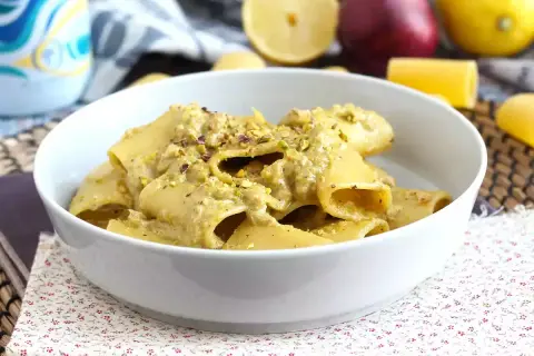 Un piatto di pasta in bianco condita con una crema di pistacchio e guarnita con granella dello stesso frutto secco.
