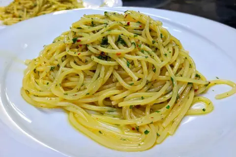 Spaghetti conditi con aglio, olio e peperoncino, guarniti con prezzemolo fresco. Un classico piatto italiano pronto da gustare.