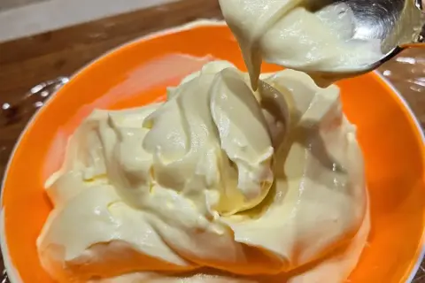 Una ciotola arancione piena di soffice crema al mascarpone, pronta per essere gustata.